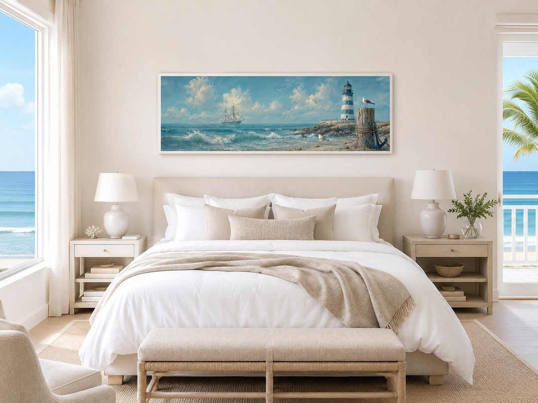 Long sailing ship and lighthouse canvas print above a bed in a coastal-style bedroom.