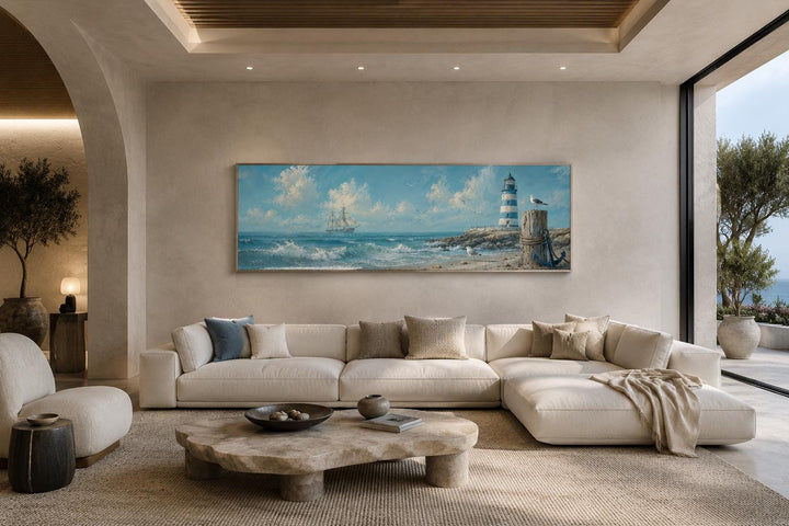 Long panoramic canvas print of a sailing ship and lighthouse in a coastal living room.
