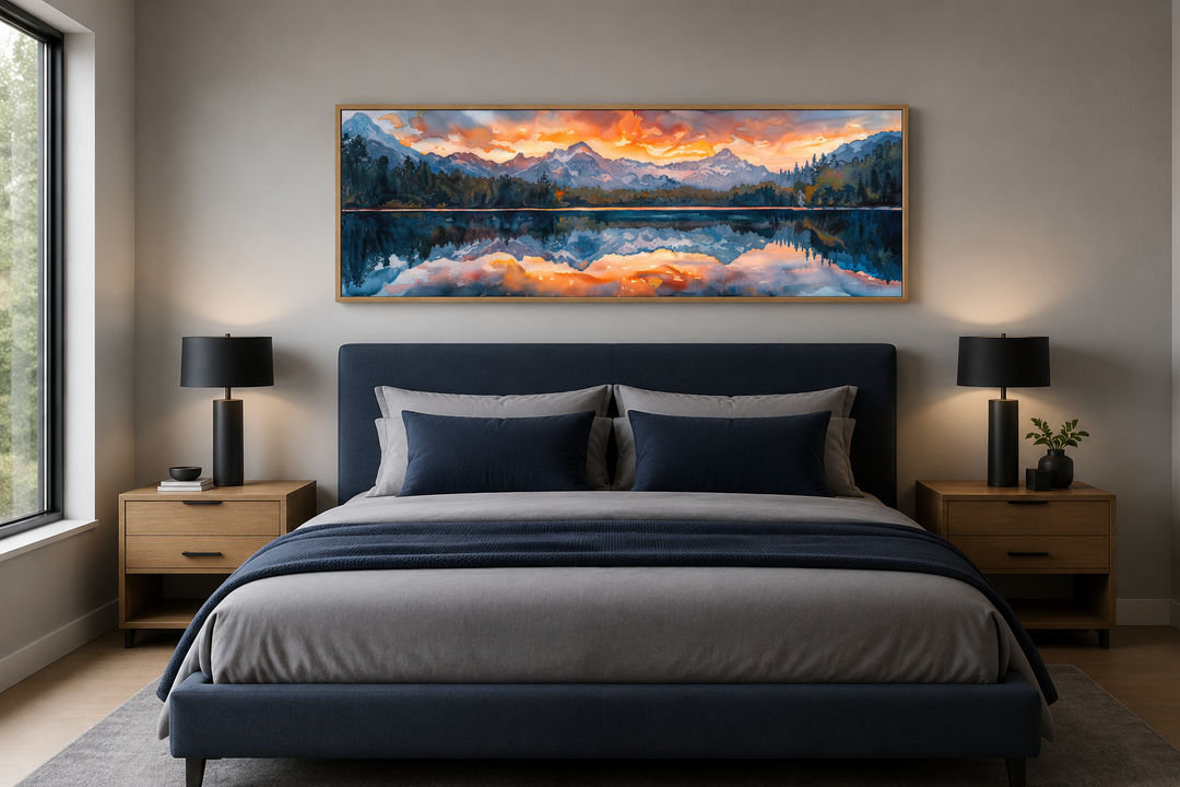 Panoramic framed canvas wall art of a sunset over a mountain lake, hung above a modern bed.