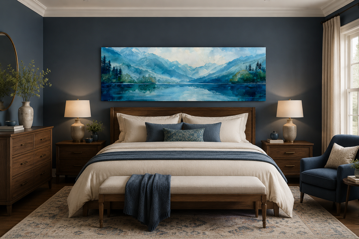 Panoramic blue and green watercolor lake landscape wall art hanging above a bed in a moody bedroom.