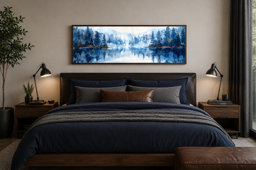 Navy blue lake watercolor landscape painting in a wood frame above a bed with navy and brown bedding.