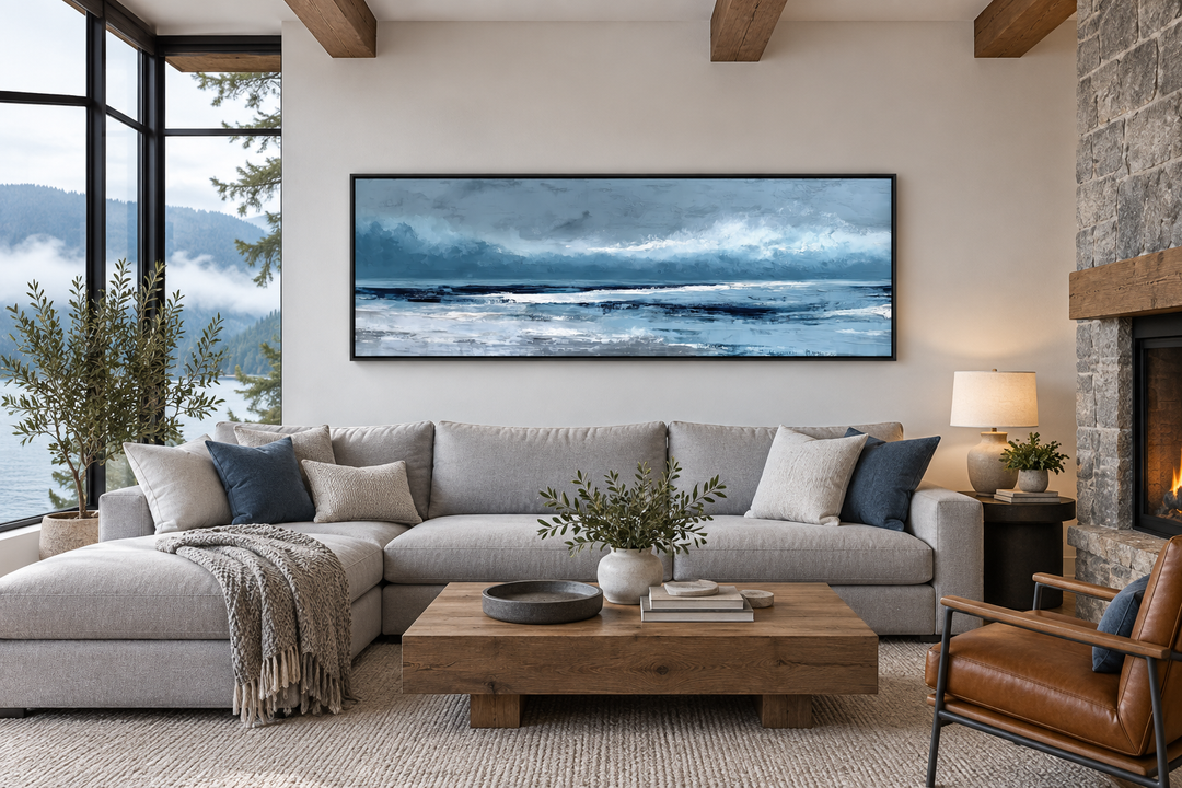 Long horizontal abstract blue ocean canvas wall art hanging above a sofa in a modern living room.