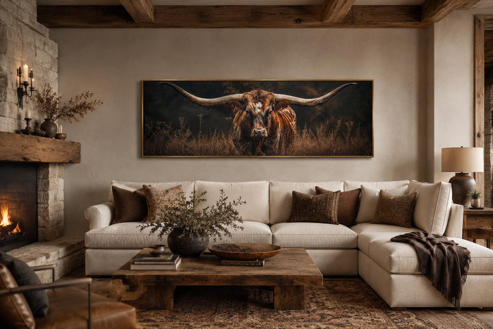 Longhorn bull canvas wall art with sweeping horns above a white sectional sofa in a rustic room.
