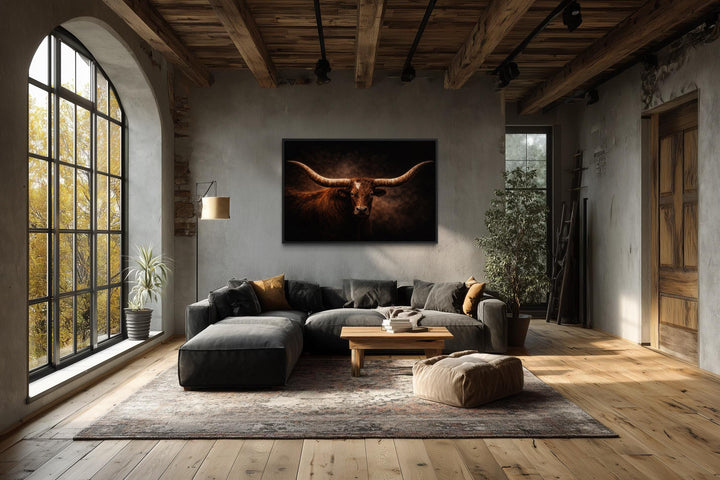 A framed canvas print of a longhorn bull with wide horns hangs in a rustic, modern living room.
