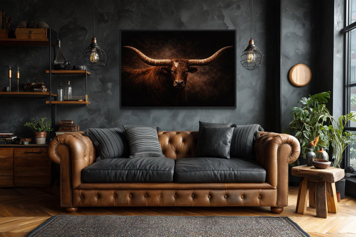 Longhorn bull canvas wall art with wide horns centered above a brown leather sofa in a rustic room.