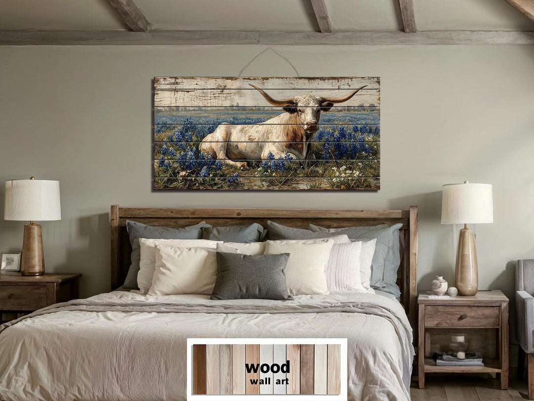 Longhorn in bluebonnet field distressed wood wall art hanging above a bed in a farmhouse bedroom.