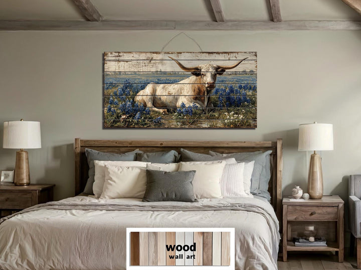Longhorn in bluebonnet field distressed wood wall art hanging above a bed in a farmhouse bedroom.