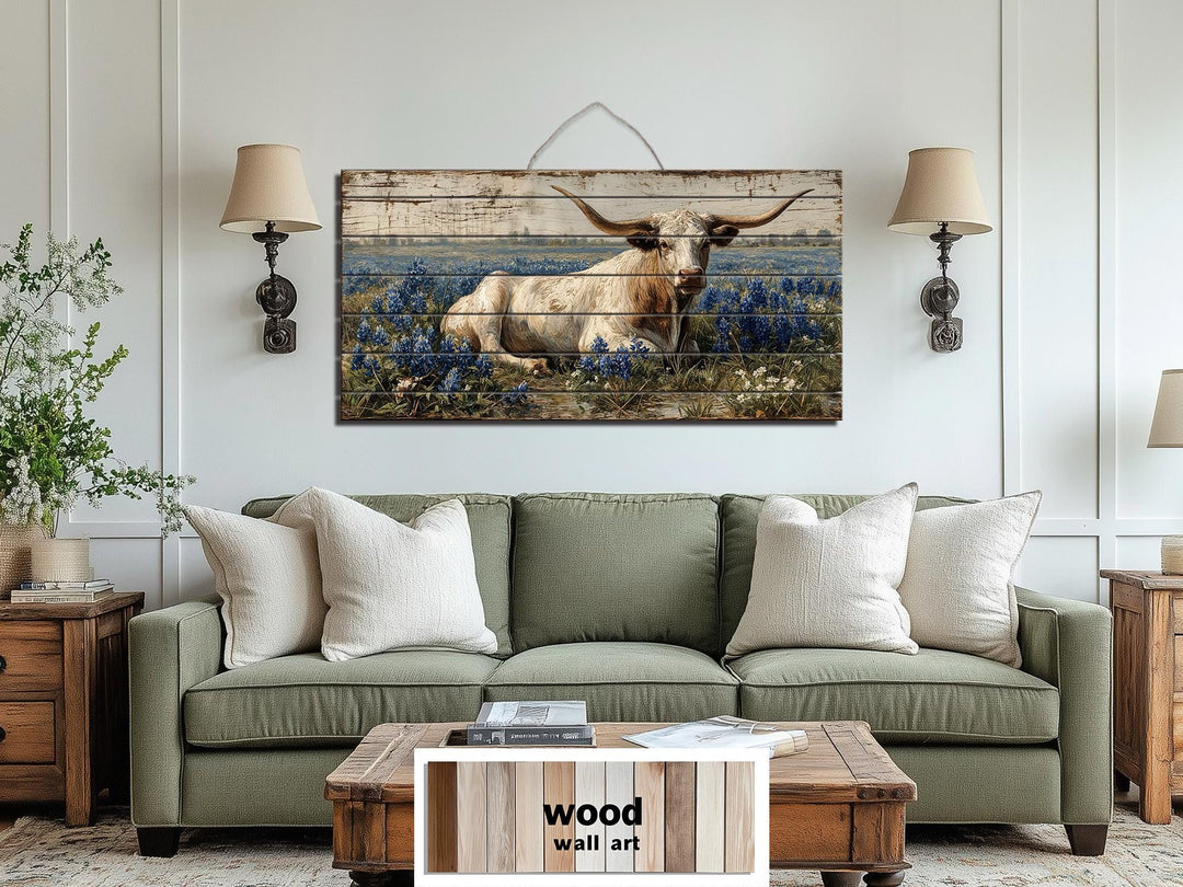 Longhorn in bluebonnet field distressed wood wall art hanging above a green sofa in a farmhouse room.