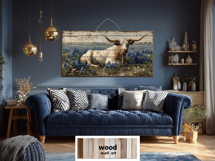 Longhorn in bluebonnet field distressed wood wall art hanging above a blue sofa in a farmhouse room.