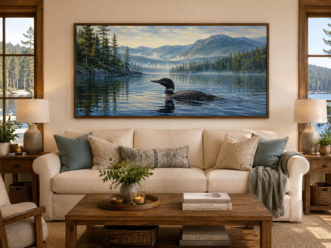 Loon wall art canvas of a common loon on a misty lake with mountains, hung above a cream sofa.
