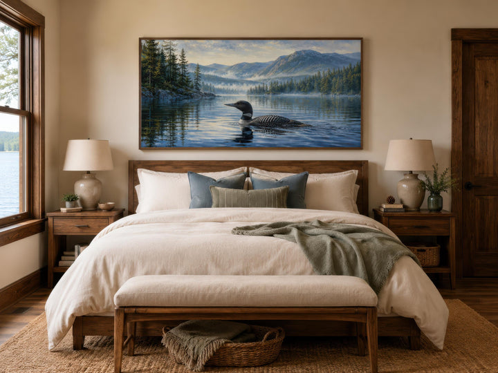 Loon wall art canvas of a common loon on a misty lake with mountains above a bed in a rustic room.