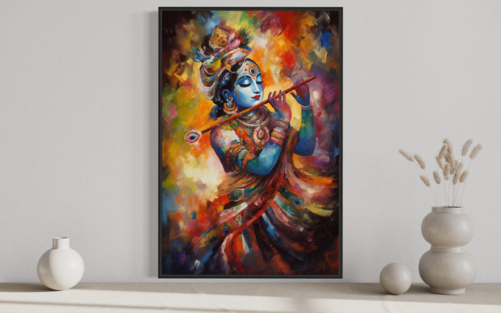 Lord Krishna playing flute colorful painting in a black frame on a white wall.