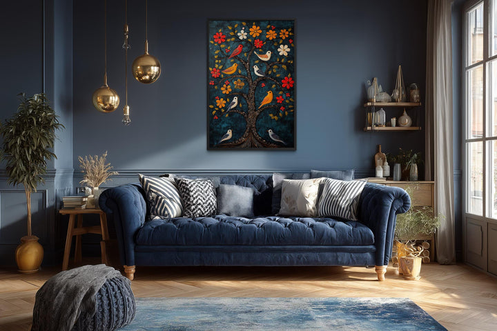 Madhubani Birds In The Tree wall art on a dark blue wall above a tufted navy velvet sofa.