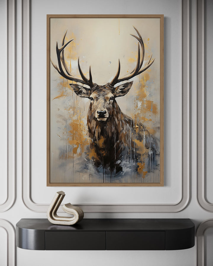Framed canvas wall art of a majestic elk portrait in beige, gold, and gray above a black console.