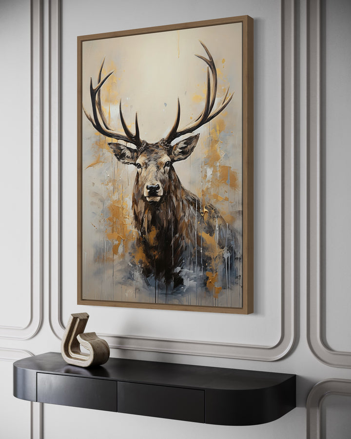 Framed abstract elk canvas art in beige, gold, and gray above a black console table.