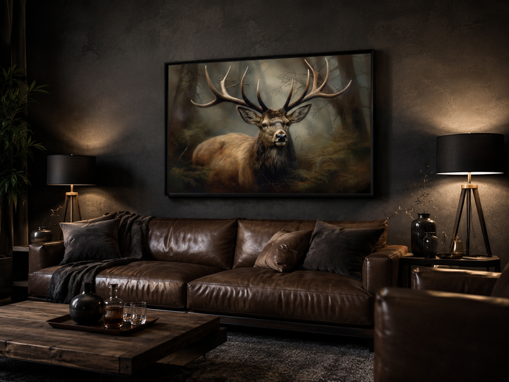 Framed canvas wall art of a majestic stag in a foggy forest above a brown leather sofa.