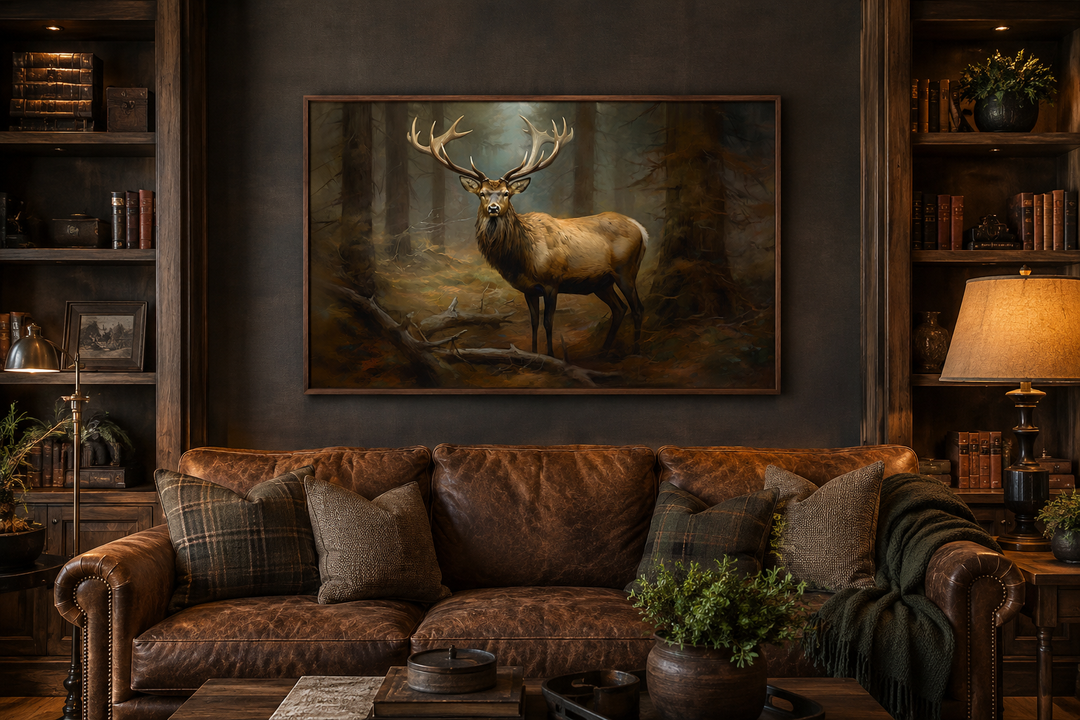 Framed canvas wall art of a majestic elk in a fir forest, displayed above a brown leather sofa.