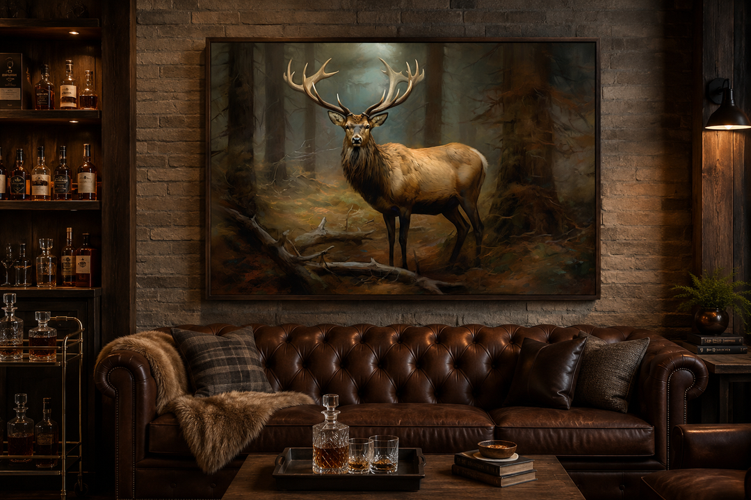 Framed canvas wall art of a majestic elk in a fir forest, displayed above a brown leather sofa.