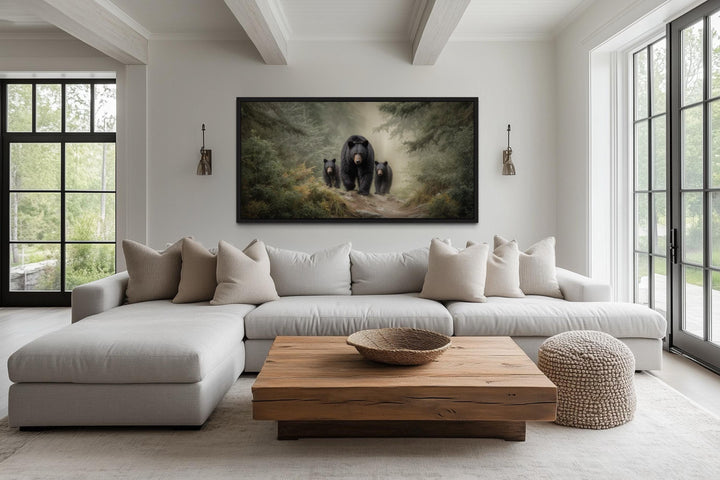 Mama bear and two cubs walking through a misty pine forest canvas wall art in a rustic living room.