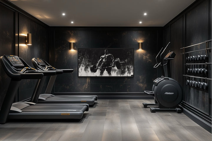 Black and white framed canvas wall art of a man doing a deadlift in a modern home gym.