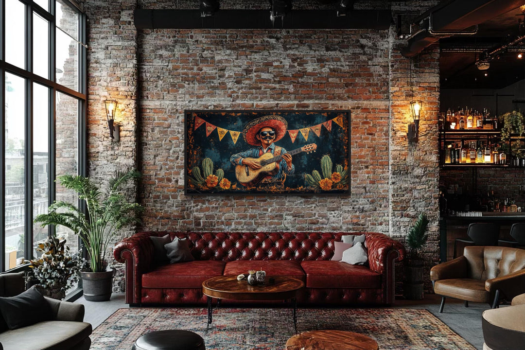 Mariachi musician in desert framed canvas wall art above a red leather sofa in a brick loft.