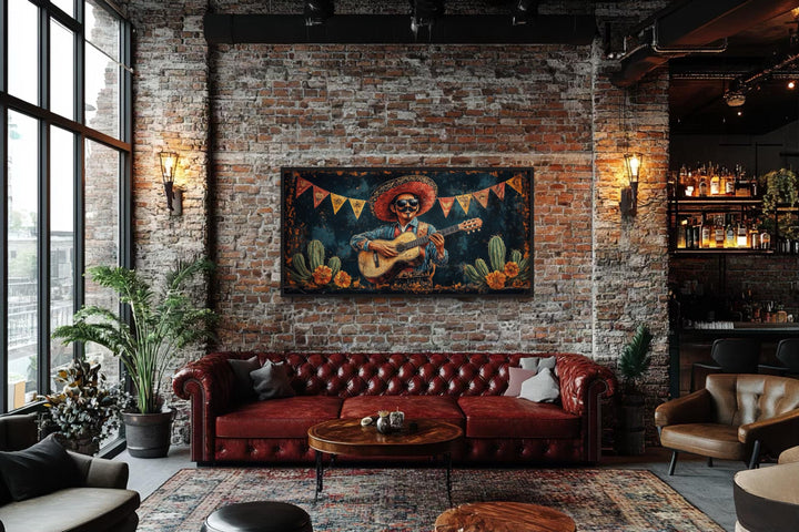 Mariachi musician in desert framed canvas wall art above a red leather sofa in a brick loft.