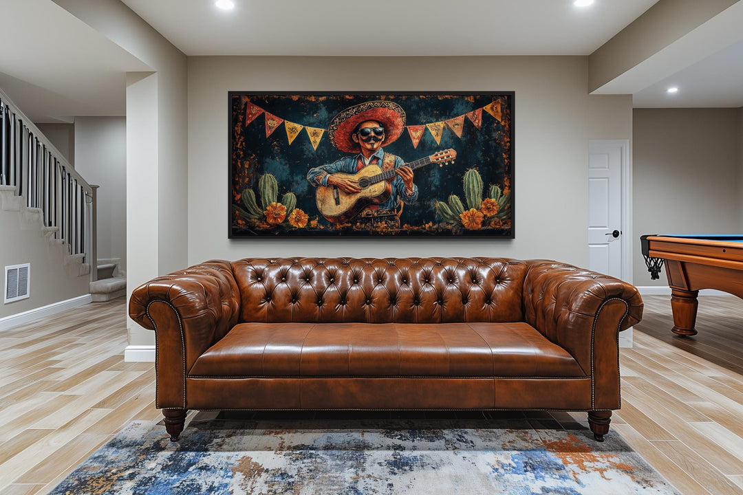 Mariachi musician playing guitar in a desert landscape framed canvas wall art above a leather sofa.