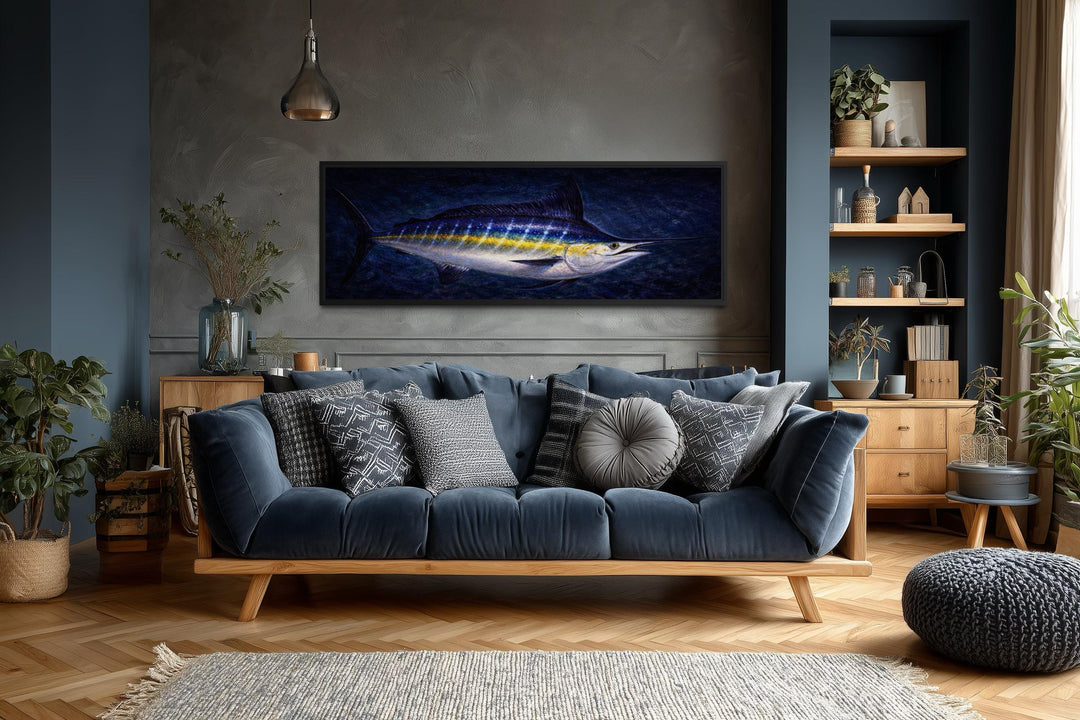 A long horizontal canvas print of a blue marlin fish hanging above a modern navy blue sofa.