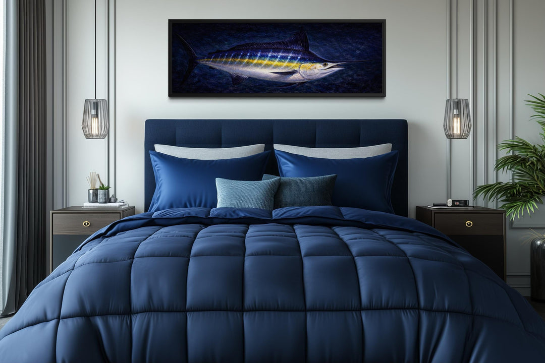 A long horizontal canvas print of a blue marlin fish hanging above a modern navy blue bed.