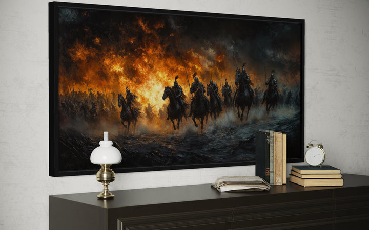 A panoramic canvas of medieval knights charging through fire and smoke, framed on a dark dresser.