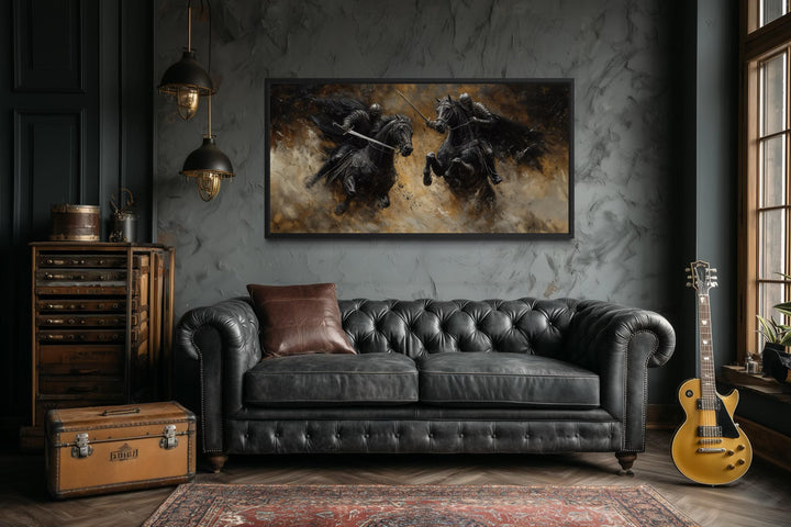 A horizontal framed canvas painting of two medieval knights dueling on horseback in a dark room.