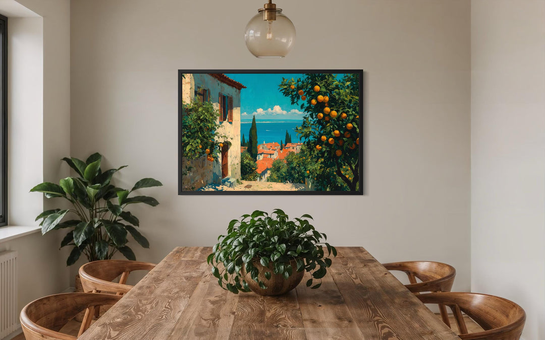 Mediterranean village canvas wall art with orange trees hanging above a wooden dining table.