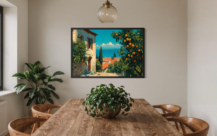 Mediterranean village canvas wall art with orange trees hanging above a wooden dining table.