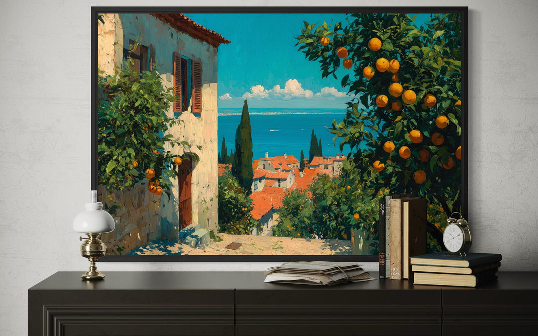 Mediterranean village canvas wall art featuring orange trees and a sea view in a black frame.