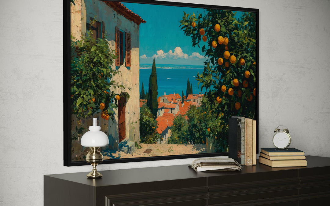 Mediterranean village canvas wall art featuring orange trees and a sea view in a black frame.