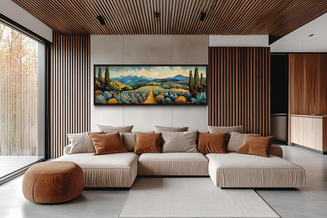 Panoramic canvas wall art of a Mexican agave field with mountains and a golden path above a sofa.