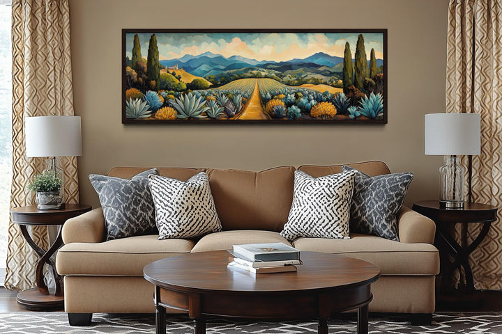 Panoramic canvas wall art of a Mexican agave field with mountains and a golden path above a sofa.