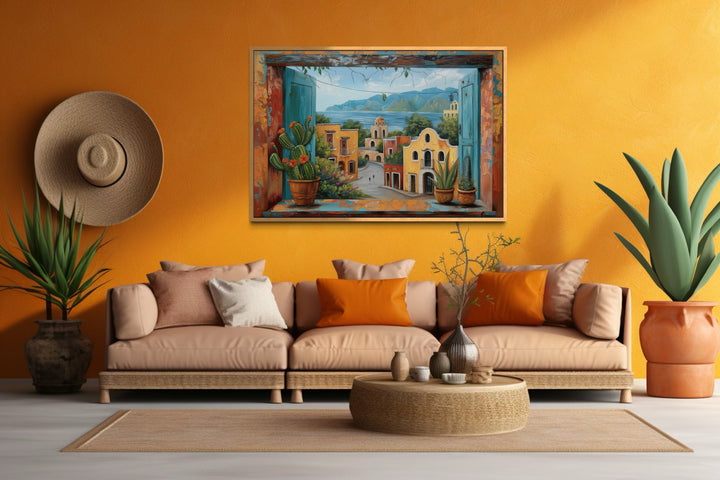 Mexican Village Window View Framed Canvas Wall Art above a tan sofa in a vibrant orange room.