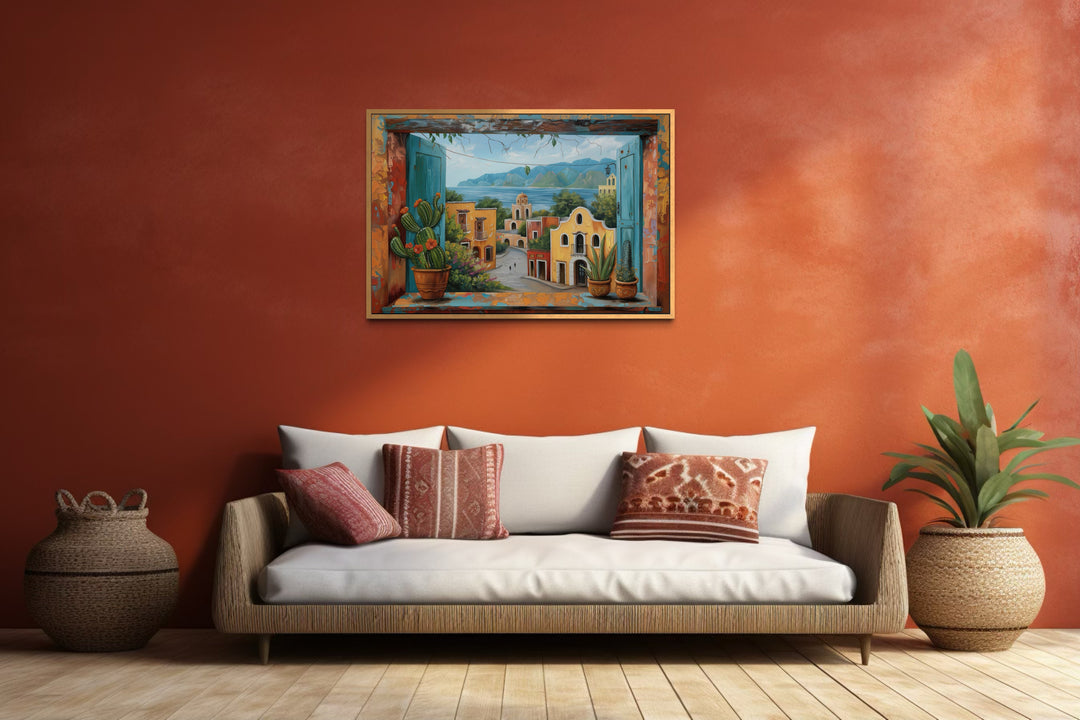 Mexican Village Window View Framed Canvas Wall Art hanging on a terracotta wall above a sofa.