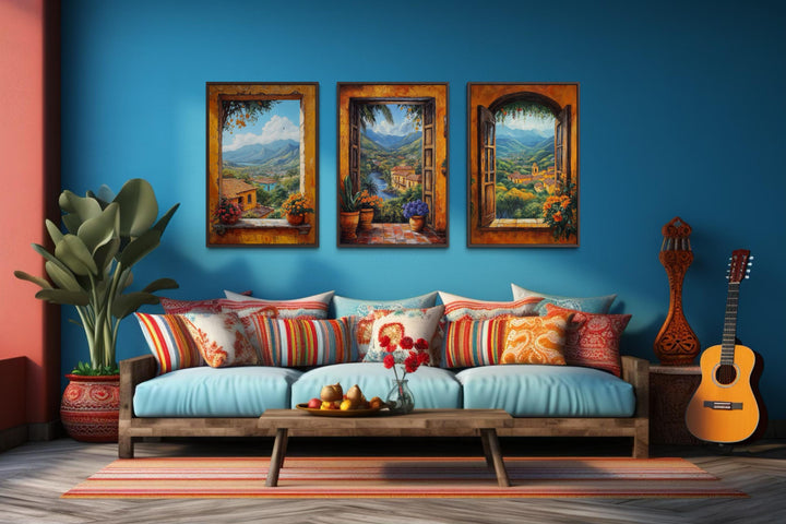 Set of three colorful canvas prints depicting scenic Mexican window views over a blue sofa.