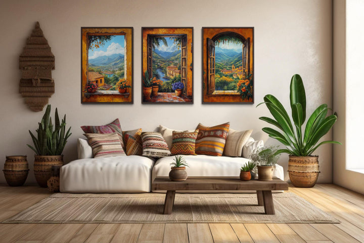Set of three Mexican window view canvas prints showing colorful hacienda landscapes over a sofa.