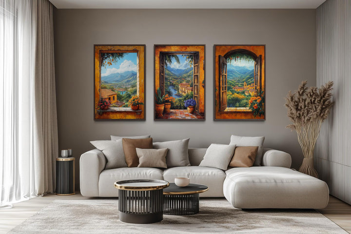 Set of three colorful canvas prints depicting scenic Mexican window views above a modern sofa.
