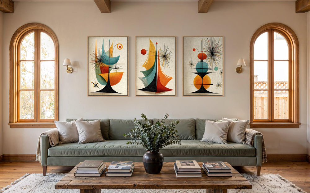 Three vertical mid-century modern abstract prints with atomic geometric shapes hang above a sofa.