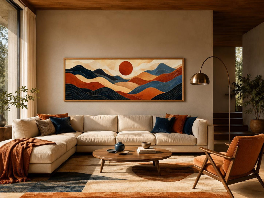 Long horizontal abstract mountain wall art in burnt orange and navy blue above a modern sofa.