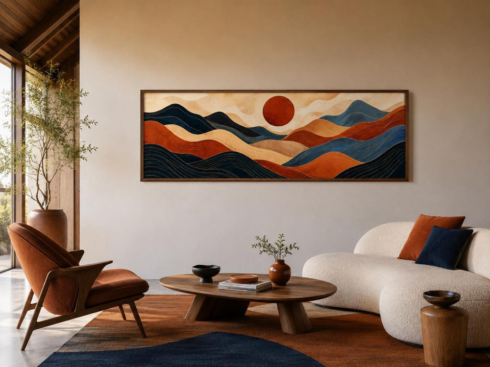 Long horizontal abstract mountain wall art in burnt orange and navy blue above a modern sofa.
