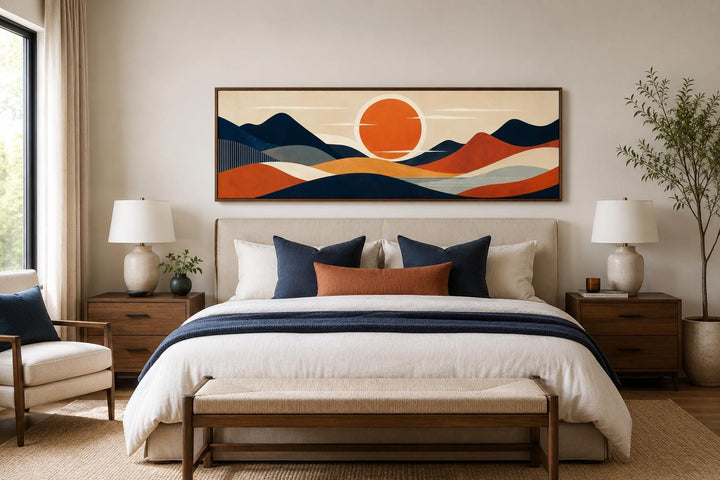 Mid-century modern navy and orange mountain sunset canvas print hanging above a bed.