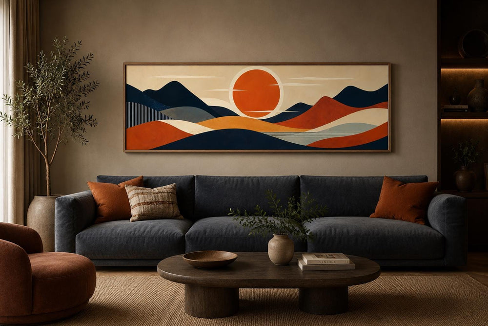 Mid-century modern navy and orange mountain sunset canvas print above a dark blue sofa.
