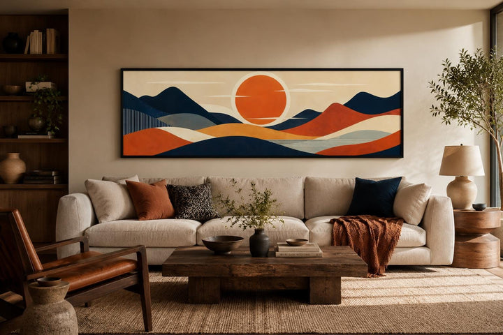 Mid Century Modern navy and orange mountain sunset canvas print above a beige sofa in a living room.