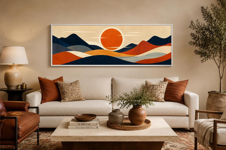 Mid-century modern navy and orange mountain sunset canvas print above a sofa in a living room.