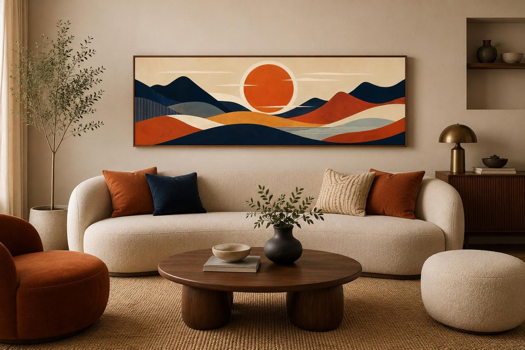 Mid-century modern navy and orange mountain sunset canvas print above a cream sofa.